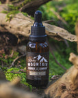 Rocky Mountain Barber Company Sandalwood Beard Oil Outdoors in Nature with Green Moss and Wood